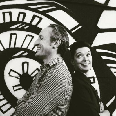 Gary and Amy, black and white, in front of a clock mural